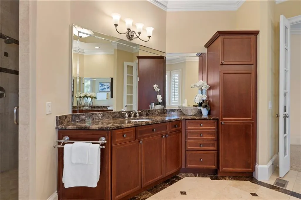 Bathroom with ornamental molding, a shower stall, inlaid floor details, vanity, and tile patterned flooring