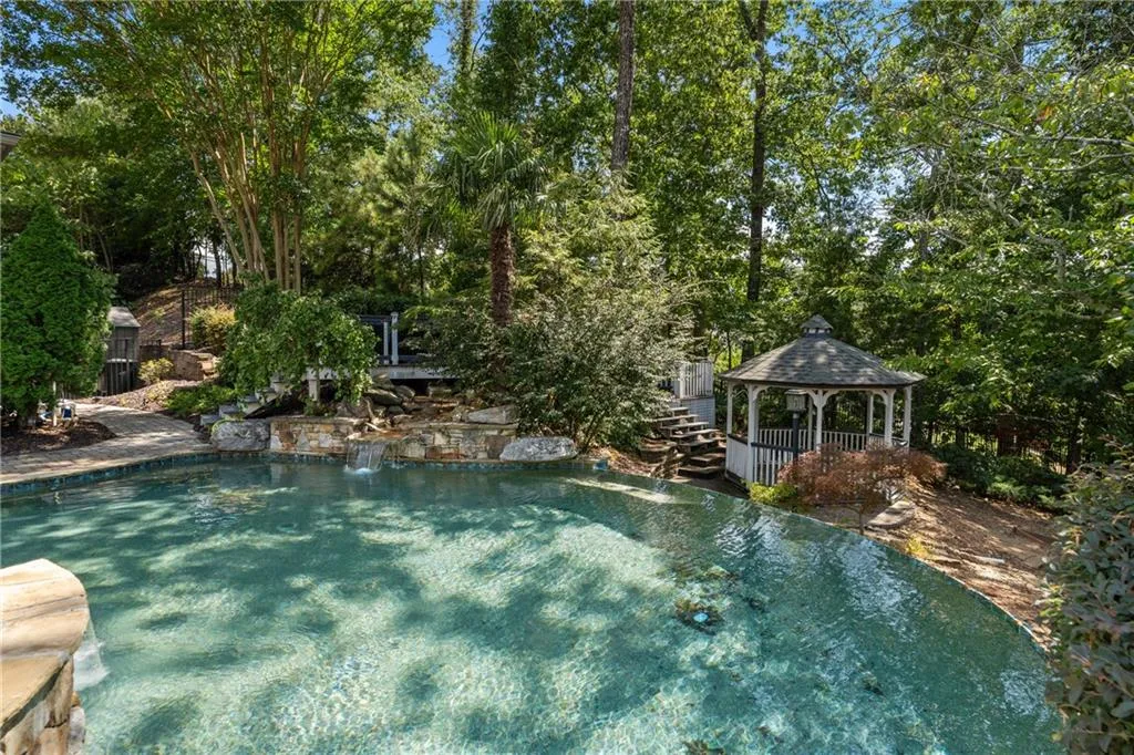 Outdoor pool with a gazebo and view of scattered trees
