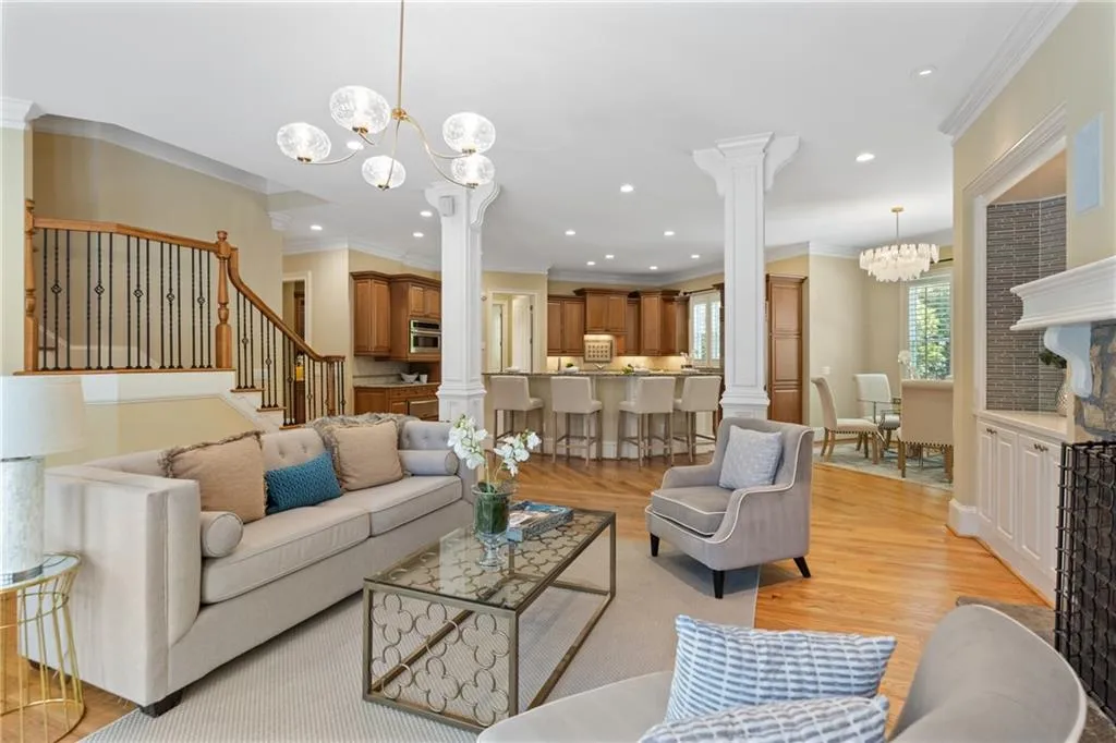 Living room with ornate columns, a chandelier, crown molding, stairway, and recessed lighting