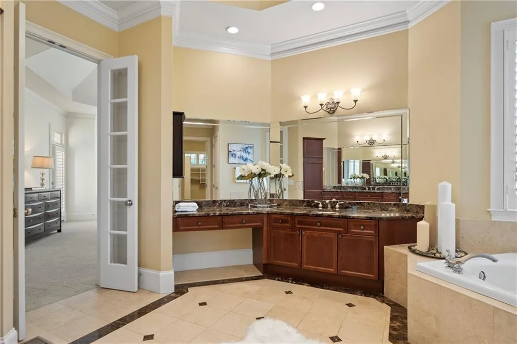 Bathroom with inlaid floor details, ornamental molding, a garden tub, a chandelier, and vanity