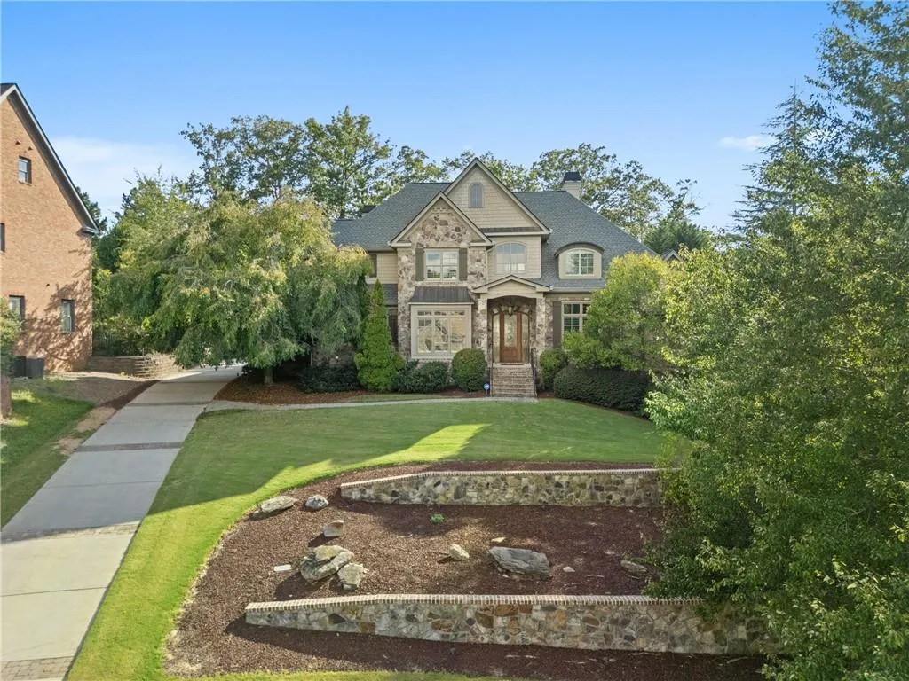 View of front of house featuring stone siding, a chimney, and a front lawn