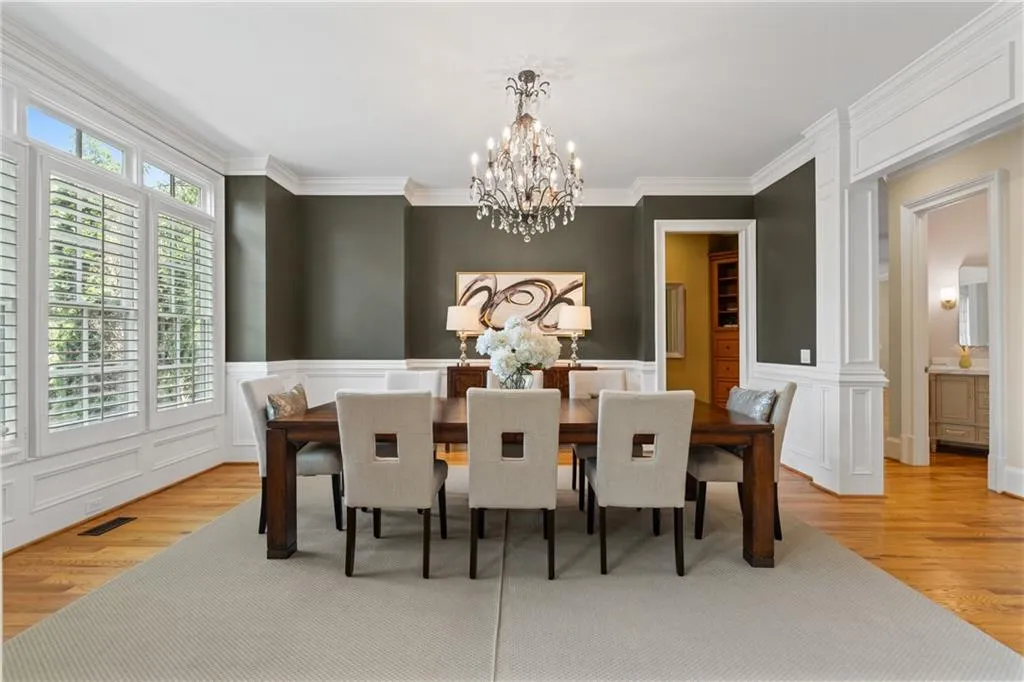 Dining space featuring a chandelier, light wood-type flooring, ornamental molding, and a decorative wall