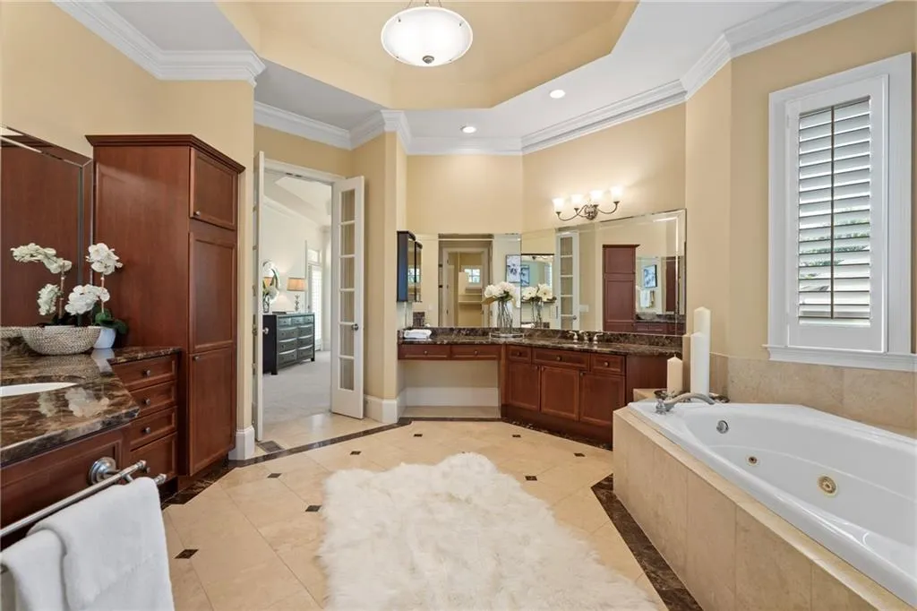 Full bath with inlaid floor details, a raised ceiling, tile patterned floors, crown molding, and vanity