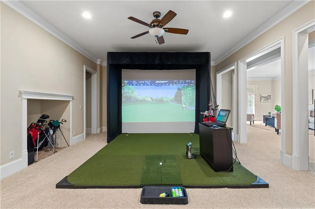 Recreation room featuring golf simulator, carpet, ornamental molding, and a ceiling fan