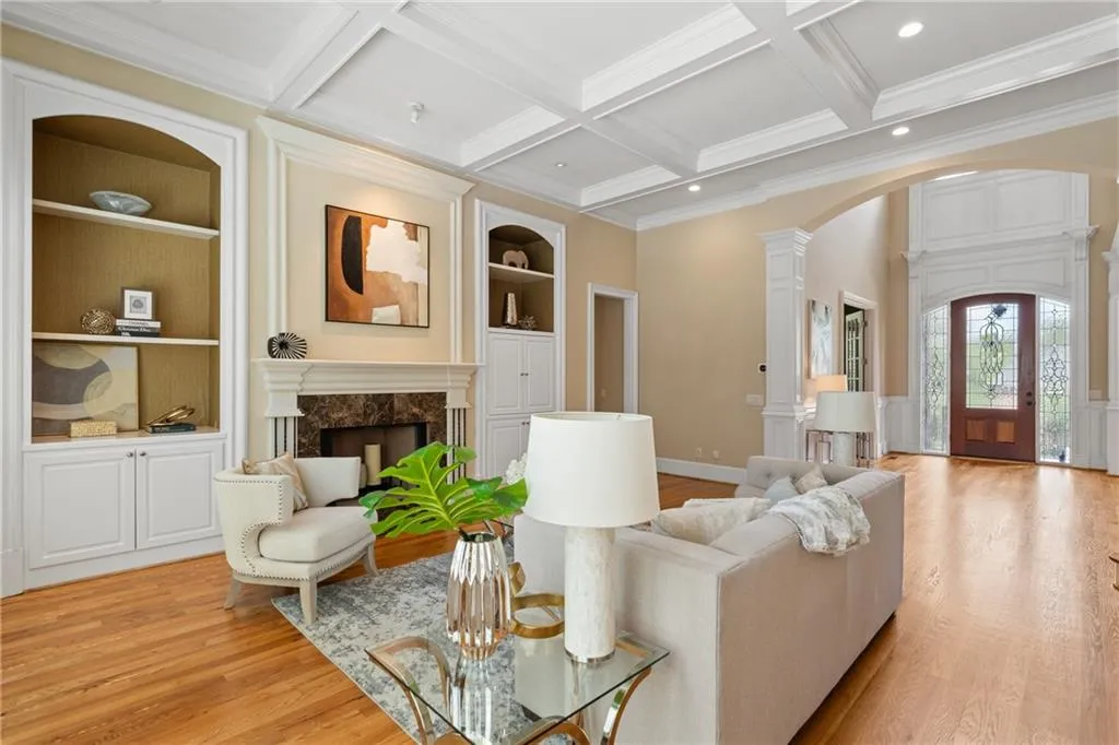 Living area with built in features, decorative columns, arched walkways, crown molding, and a high end fireplace