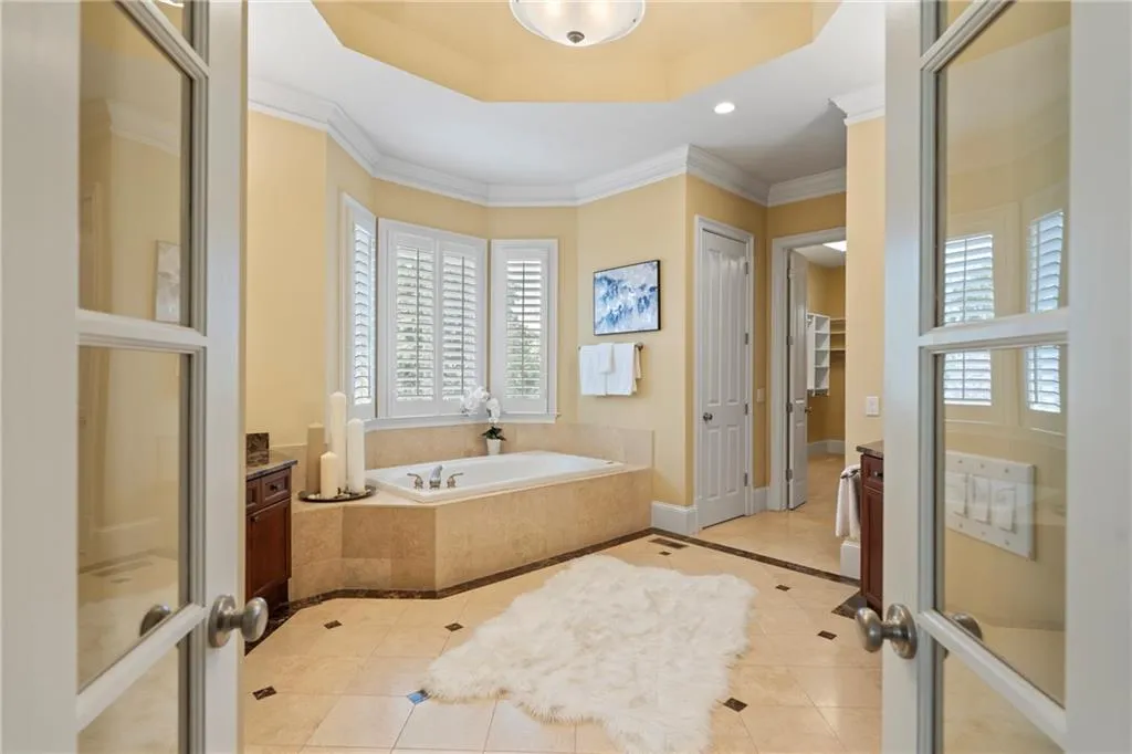 Bathroom featuring tile patterned flooring, a bath, inlaid floor details, crown molding, and recessed lighting