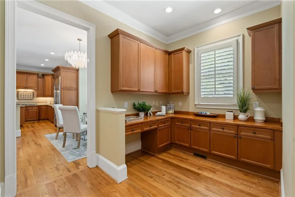 Kitchen featuring crown molding, light wood-style floors, recessed lighting, brown cabinetry, and built in study area