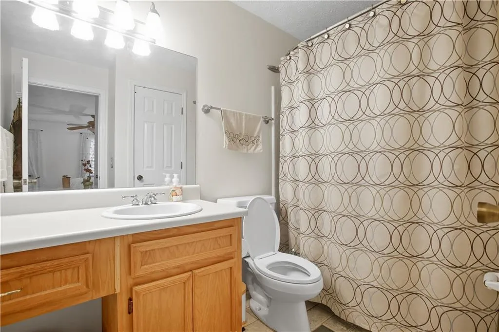Bathroom featuring vanity, curtained shower, ceiling fan, and light tile patterned floors