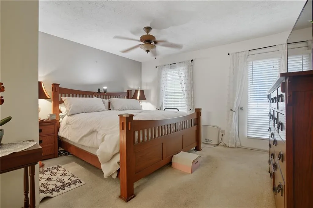 Bedroom with light carpet, a ceiling fan, and a textured ceiling