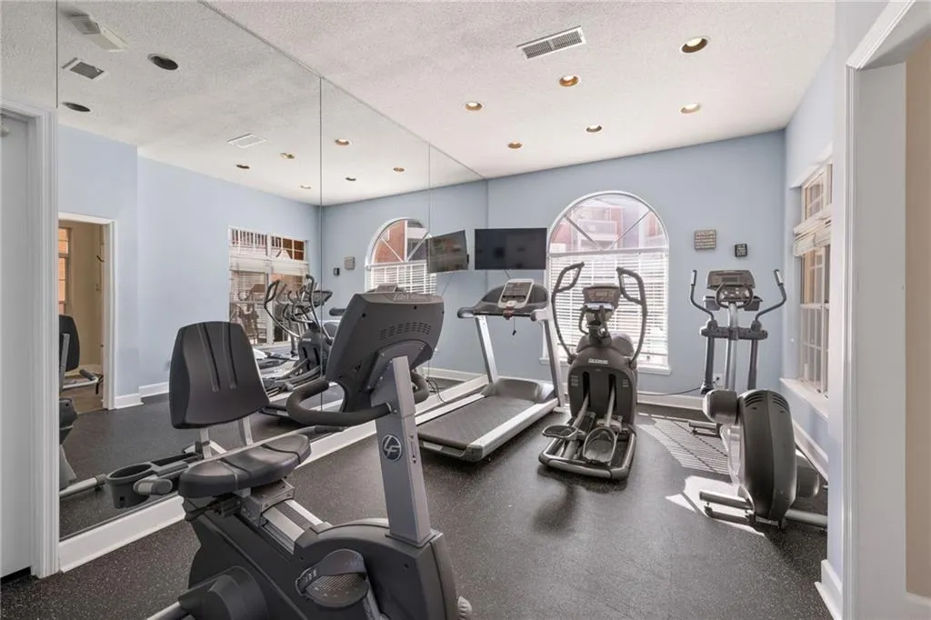 Dedicated fitness area featuring rubberized flooring, recessed lighting, and mirrored walls