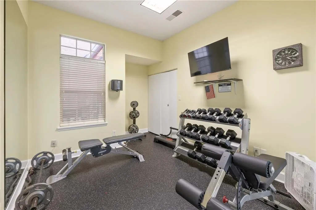 Dedicated exercise space featuring durable rubber flooring, a window with blinds, and recessed lighting