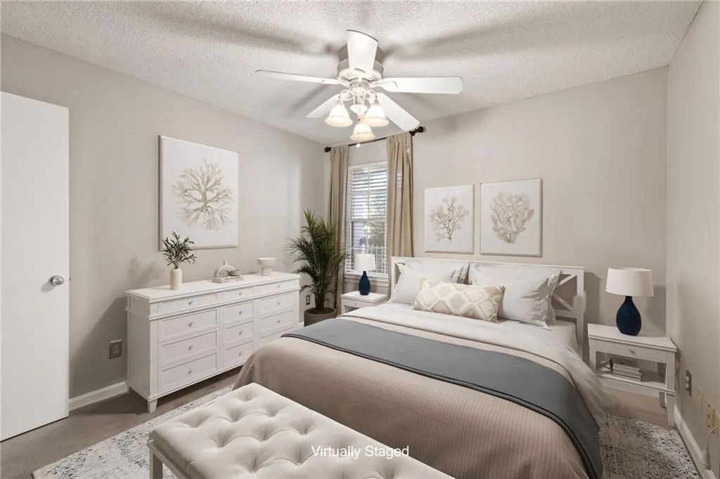 Neutral wall paint, white ceiling fan with light fixture, window with blinds, and light-colored carpeting
