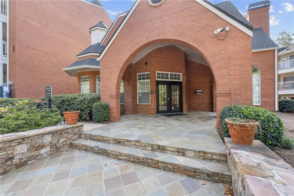 Welcoming brick entrance with a dramatic arched portico, stone-paved approach, and manicured landscaping
