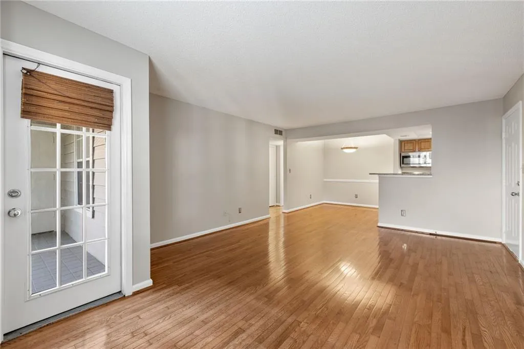 Hardwood flooring throughout, neutral paint palette, pass-through serving counter, recessed dining area, and a white paneled door