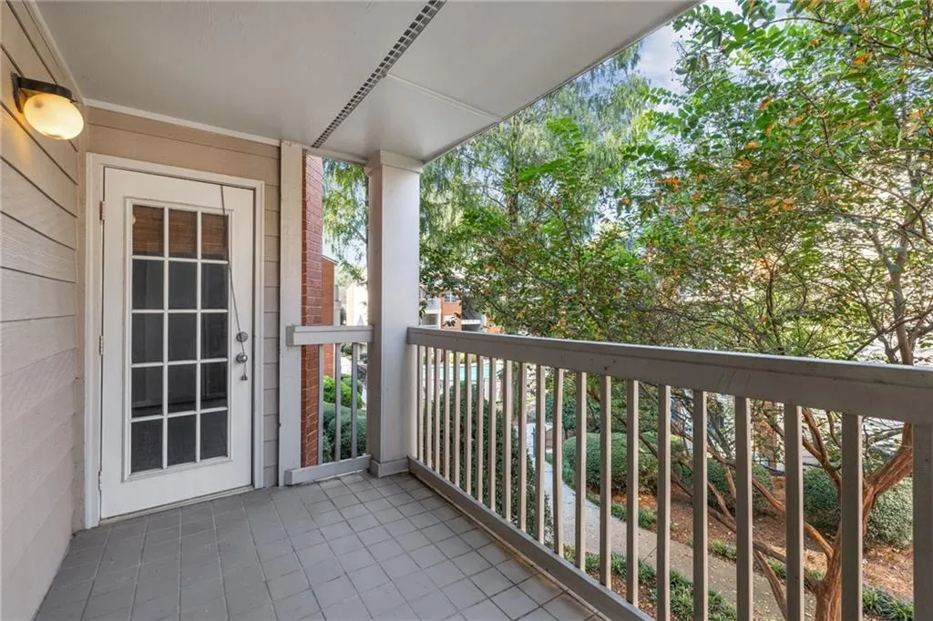 Private balcony with a tiled floor, white railing, and a glass-paned door