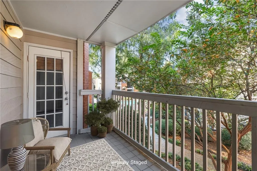 Covered balcony with a paneled door featuring multiple glass lites, a white railing, and exterior wall sconce