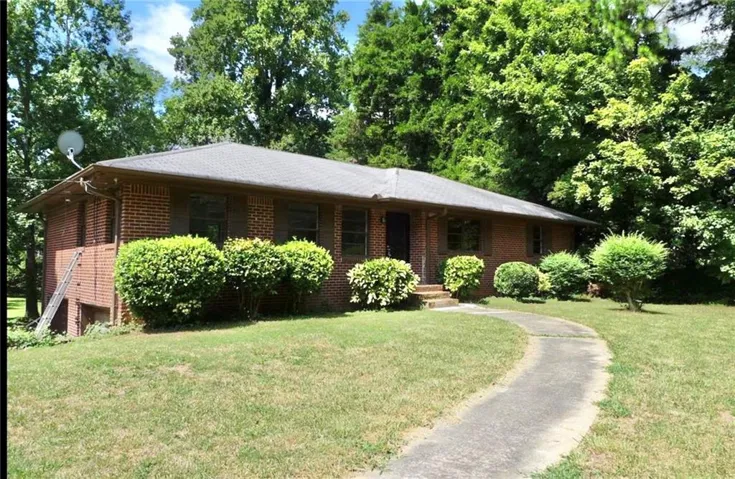 Brick exterior with a dark shingle roof and mature landscaping