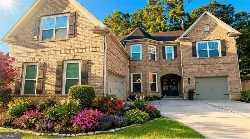 Brick exterior with multiple gables, two-car garage, arched entry, and mature landscaping