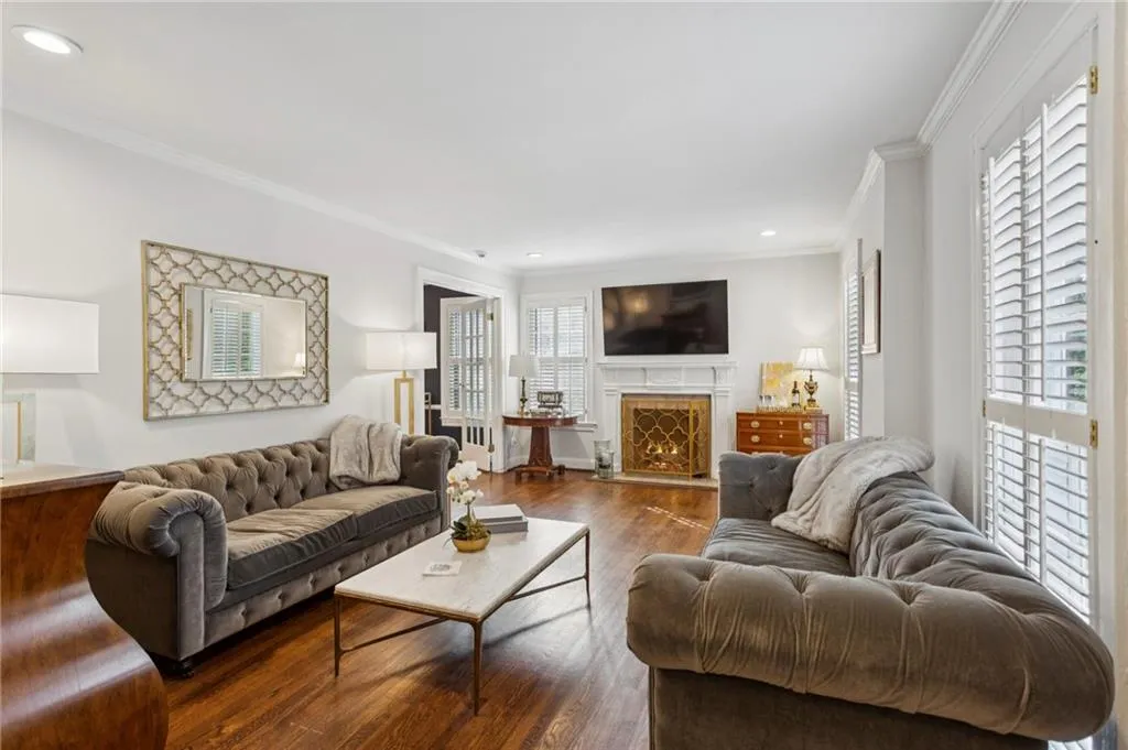 Living area with a lit fireplace, wood finished floors, ornamental molding, and recessed lighting