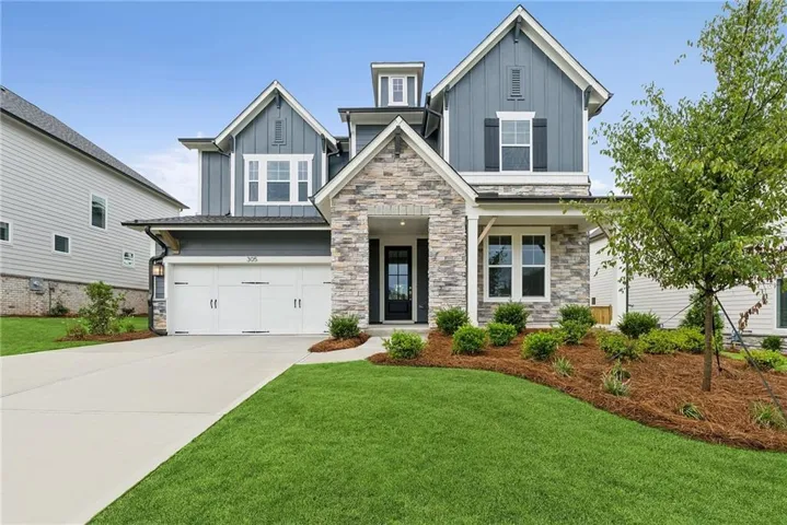 Contemporary exterior featuring board and batten siding, stone accents, and a two-car garage