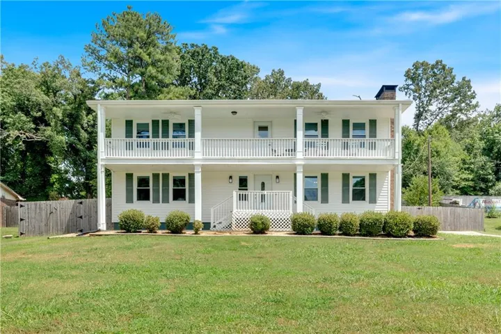 Two-story residence featuring white siding and dark green window shutters
