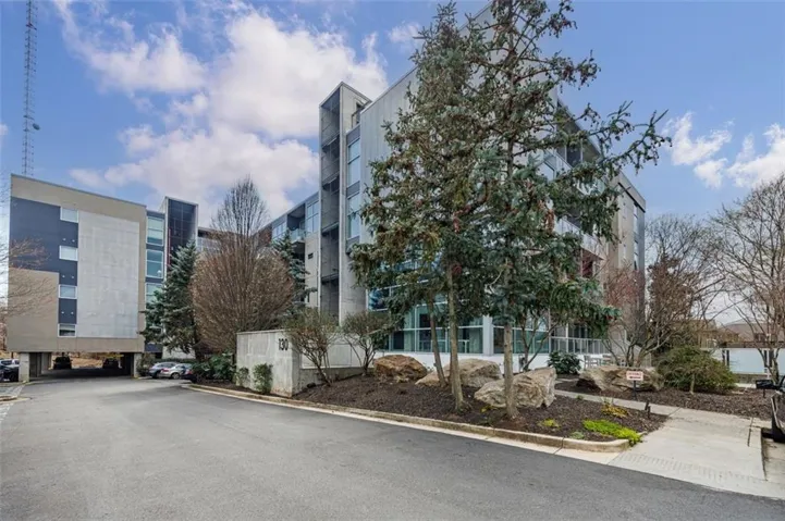 Contemporary multi-story building featuring extensive glazing, multiple balconies, and a concrete facade