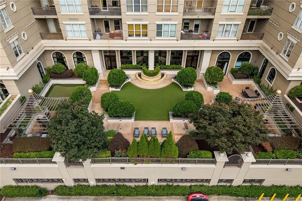 Manicured courtyard with artificial turf, mature landscaping, and a central water feature