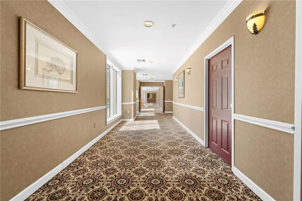 Patterned carpeting, light-colored walls, white crown molding, recessed lighting, and wall-mounted sconces