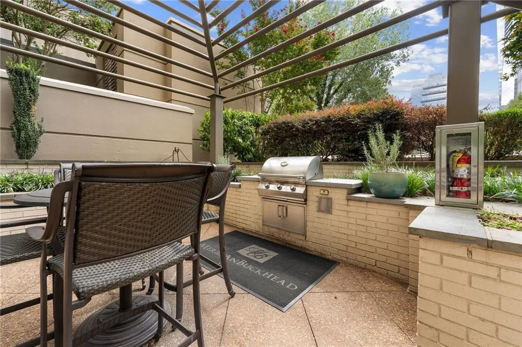Outdoor patio featuring a built-in stainless steel grill, brick half-wall, and an overhead trellis structure