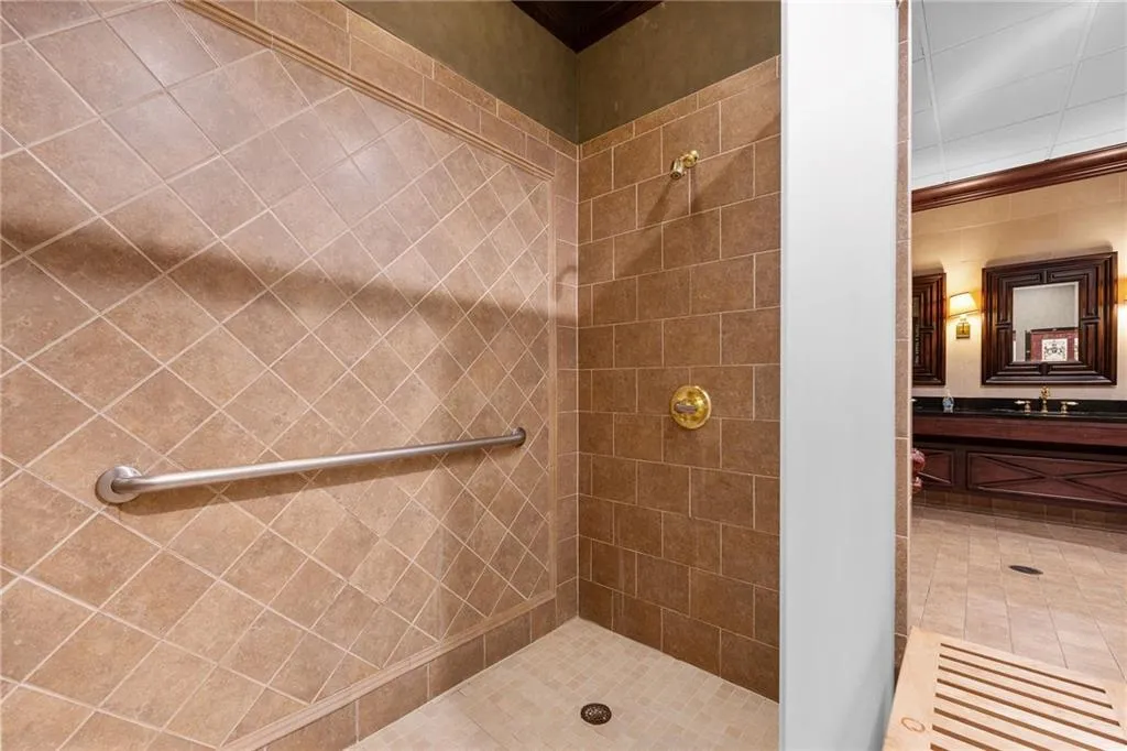 Tiled shower enclosure with brass fixtures and a grab bar