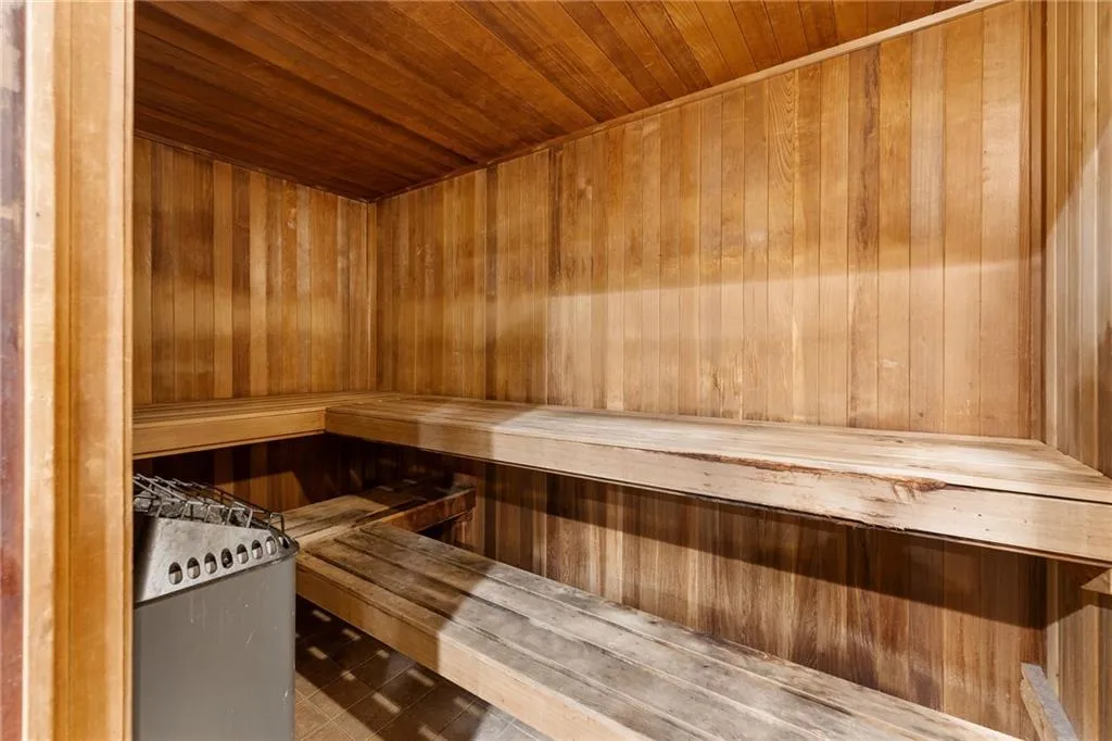 Wood-paneled sauna featuring a built-in heater, tiered seating, and wood-slat ceiling