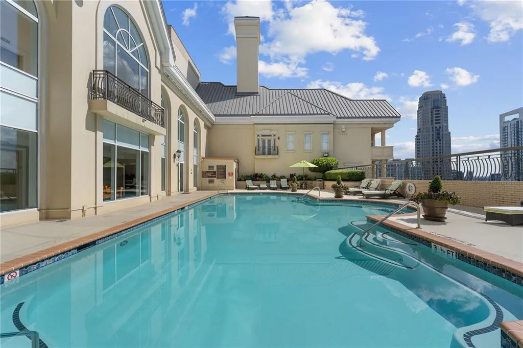 Outdoor swimming pool with integrated steps, surrounded by a concrete deck with brick trim