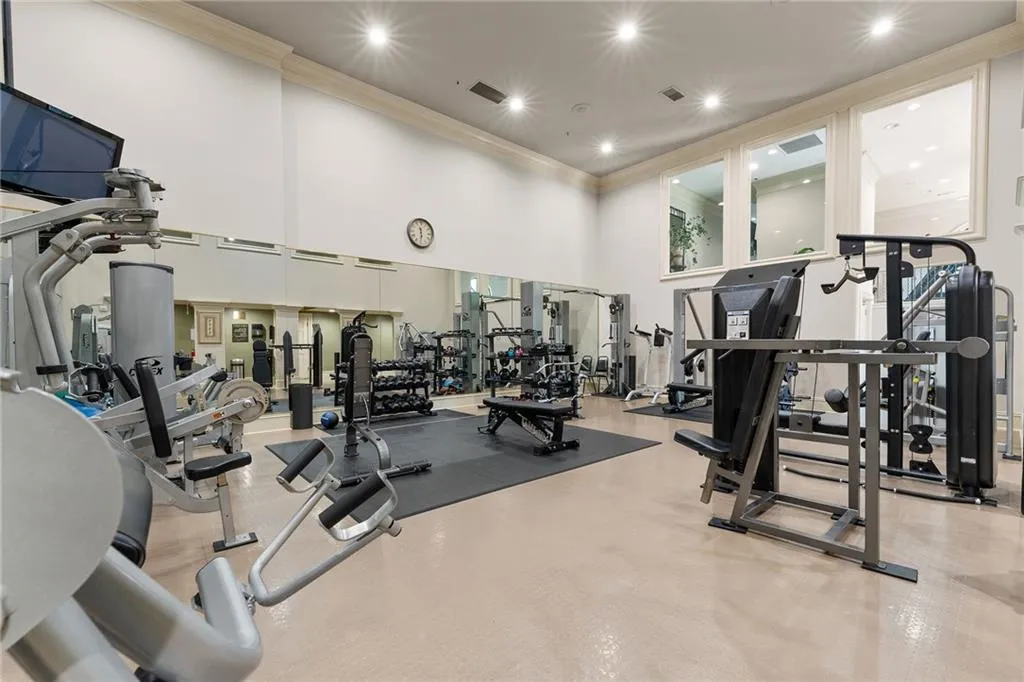 Spacious fitness area featuring high ceilings, recessed lighting, mirrored wall, and three upper windows