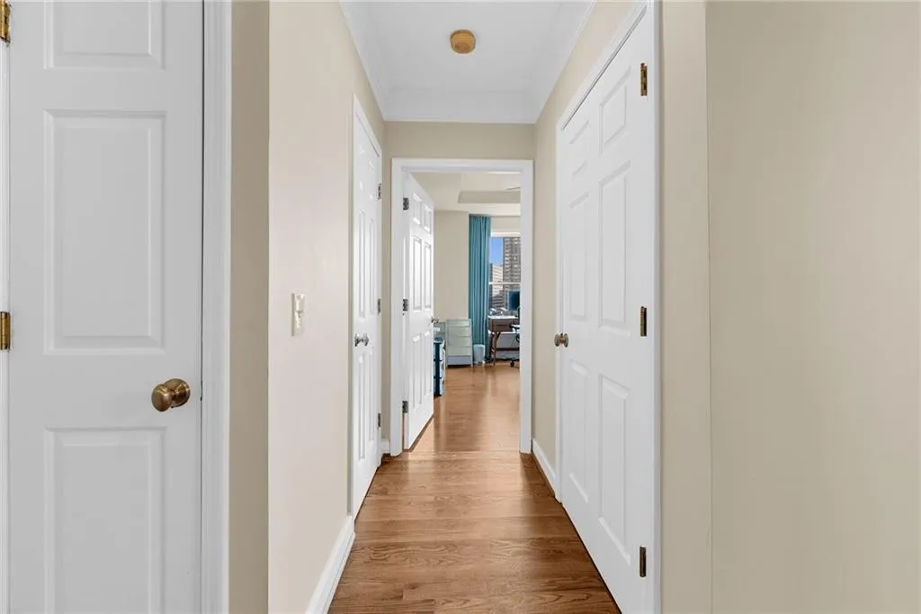 Hallway featuring wood-finish flooring, crown molding, and paneled doors