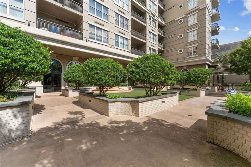 Expansive courtyard with manicured shrubbery, brick planters, and a contemporary building exterior
