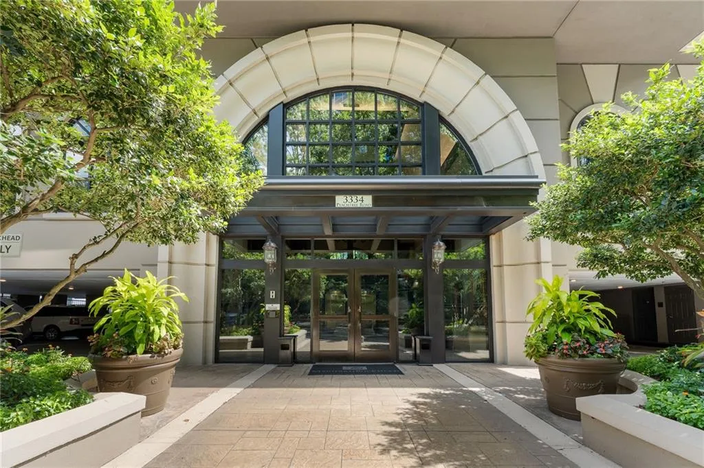 Building entrance with a large arched window, glass double doors, a protective overhang, and decorative planters