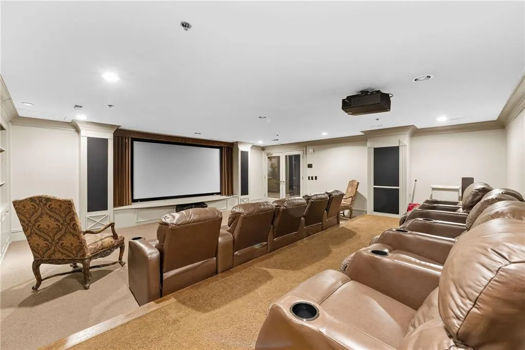 Dedicated home theater featuring a large projection screen, recessed lighting, and crown molding