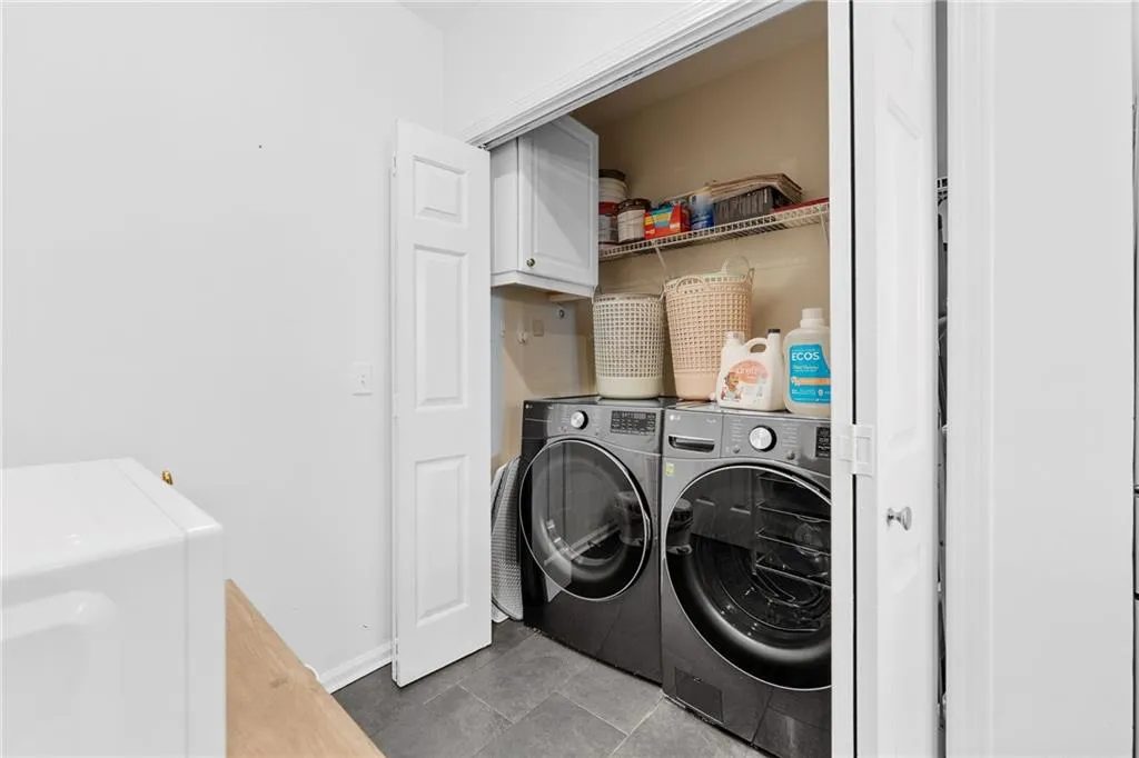 Laundry area with a built-in shelf and overhead cabinetry