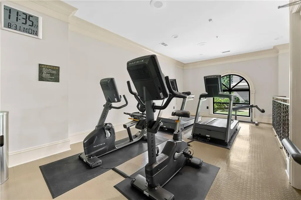 Dedicated fitness area with a large arched window, crown molding, and recessed lighting