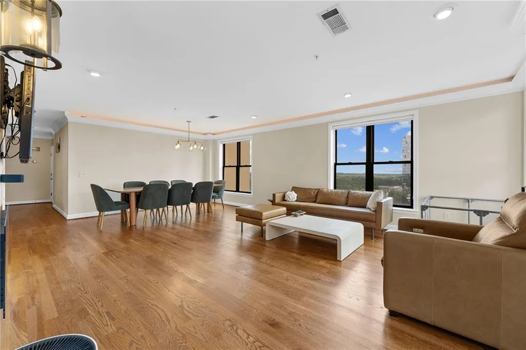 Open-concept living area featuring wood-finish flooring, crown molding, recessed lighting, and expansive windows