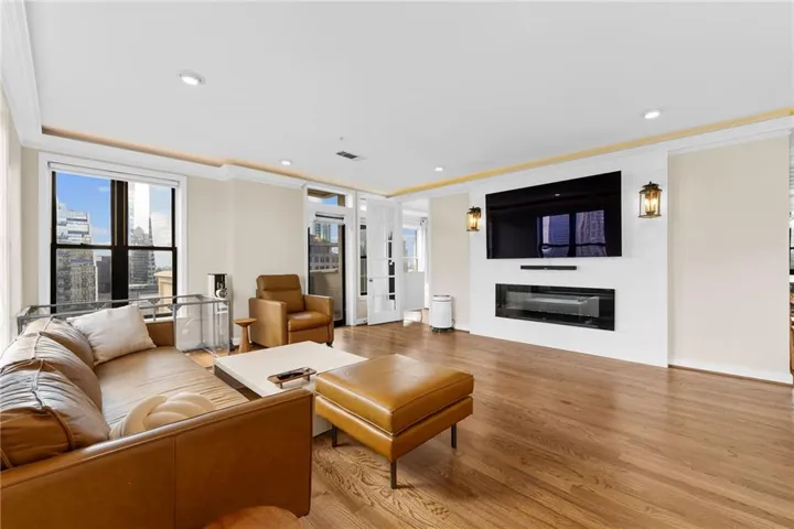 Hardwood flooring throughout, built-in electric fireplace, recessed lighting, crown molding, and large windows