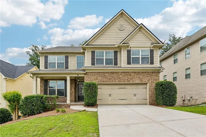 Two-story residence featuring a two-car garage, brick facade, and a covered front porch
