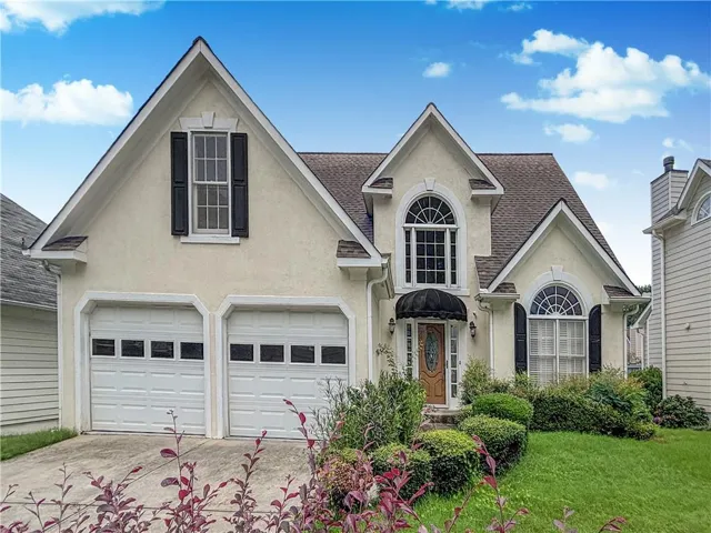 Stucco exterior featuring multiple gables and a covered entry