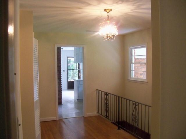 Hall with dark wood-type flooring and a chandelier
