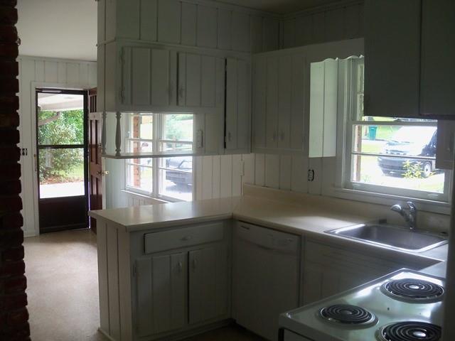 Kitchen with sink, kitchen peninsula, white dishwasher, and stove