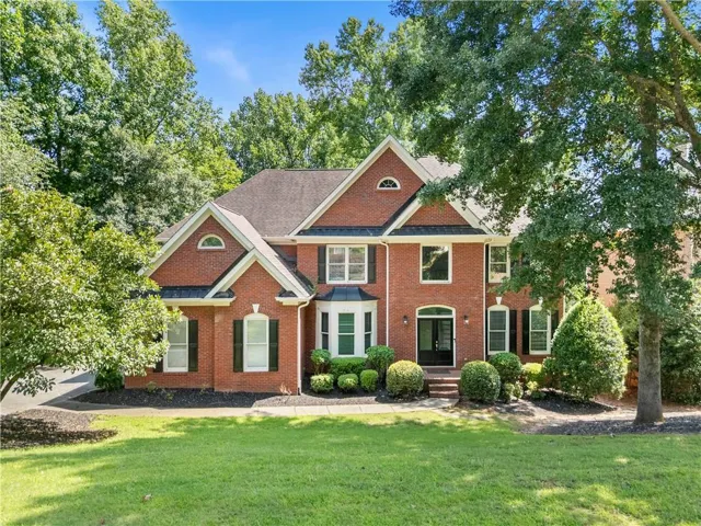 Brick exterior residence featuring a gabled roofline and dark shutters