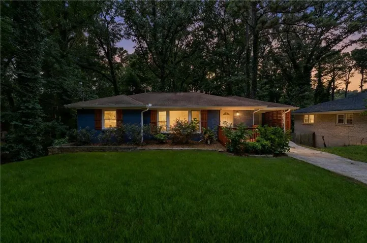 Blue exterior facade, brown shutters, front yard landscaping, paved driveway, mature trees