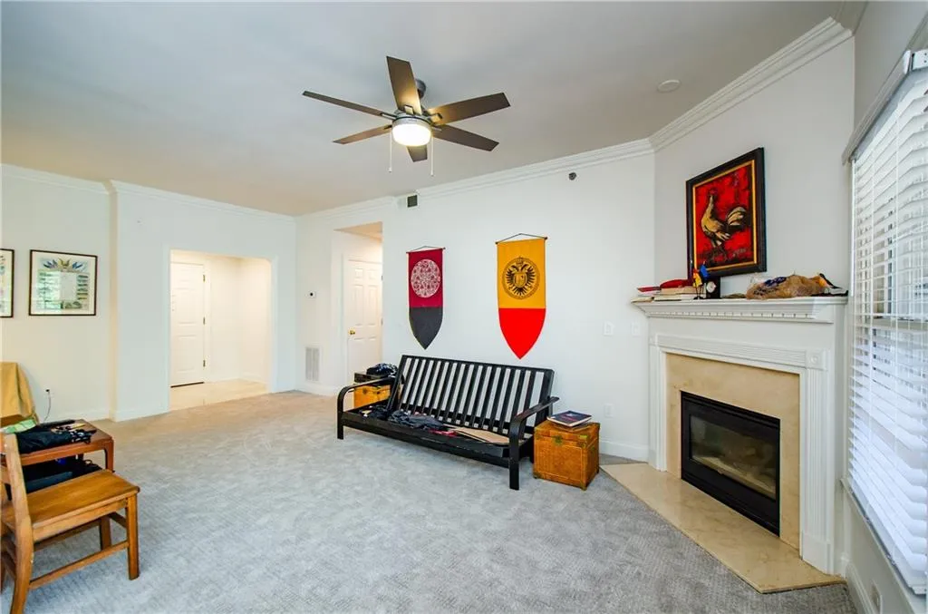 Living area with carpet flooring, ornamental molding, a ceiling fan, and a fireplace