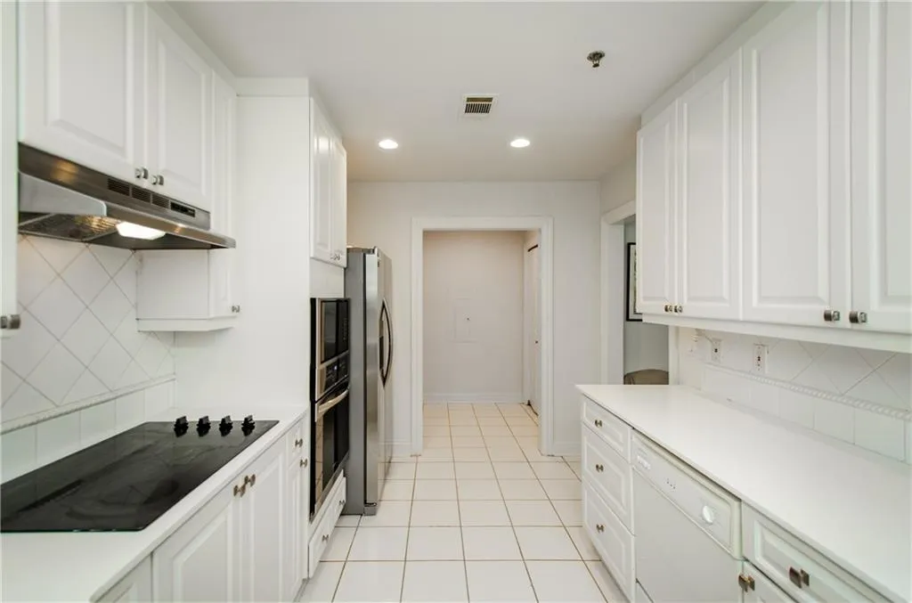 Kitchen with under cabinet range hood, stainless steel appliances, white cabinets, and recessed lighting