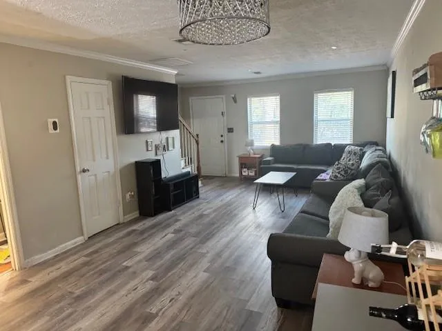 Living area featuring a textured ceiling, crown molding, and wood finished floors